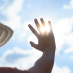 Photo of woman holding hand over sun to shield her eyes