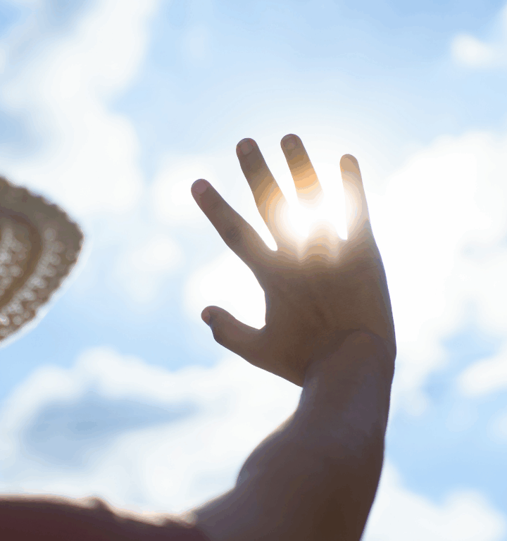 Photo of woman holding hand over sun to shield her eyes